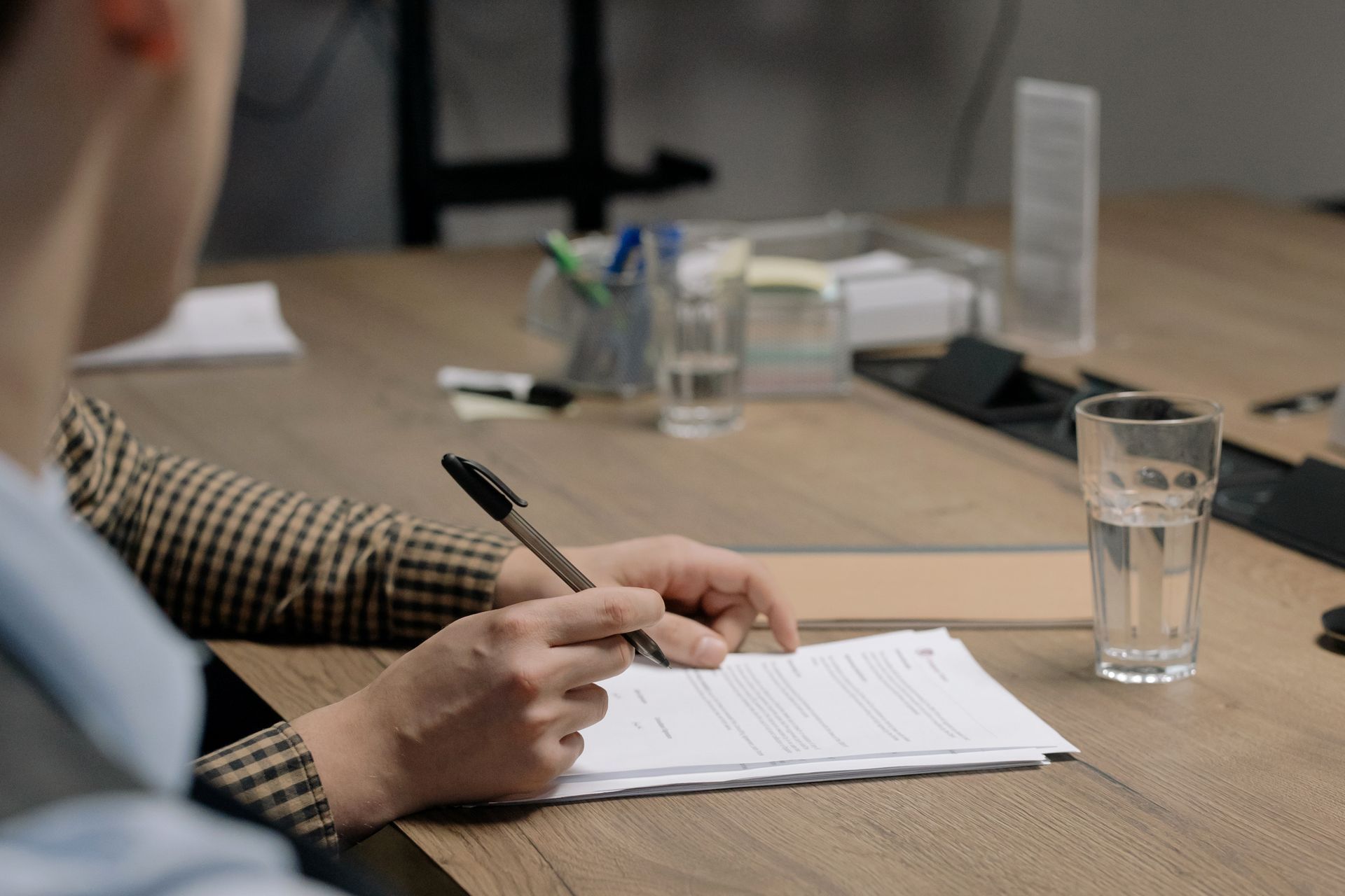 Pessoa faz anotações em documentos sobre uma mesa de reunião